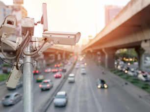 Close-up of traffic surveillance cameras monitoring vehicles on a busy highway in a city environment