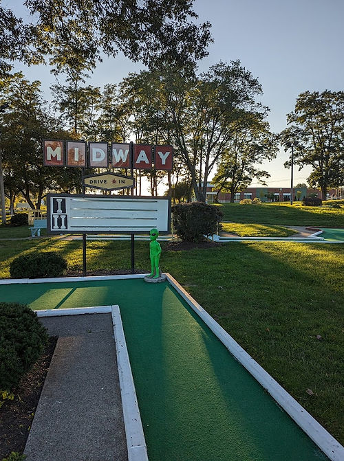 Mini folg hole featuring green alien and a replica drive-in movie theater sign.