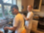 two bright faced Krishna devotees are cooking and smiling at the camera