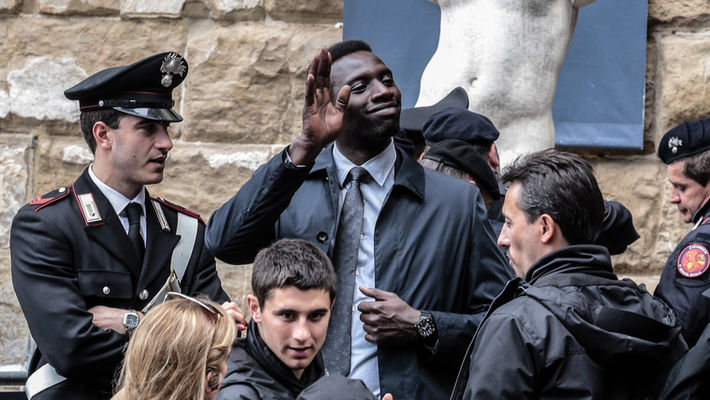 Omar Sy durante le riprese del film Inferno a Firenze, sotto la statua del David di Donatello, mentre saluta i fan.