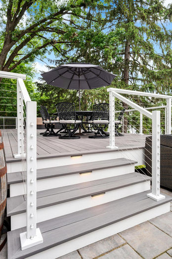 Outdoor living terrace with decking, railing, Island Cap lighting, and kitchen overlooking the lake in Grayslake IL built by OnDeck