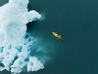 Drone shot from above kayakers next to large blue iceberg