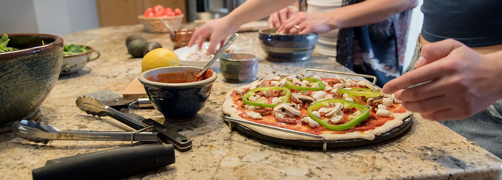 two sets of hands making pizza