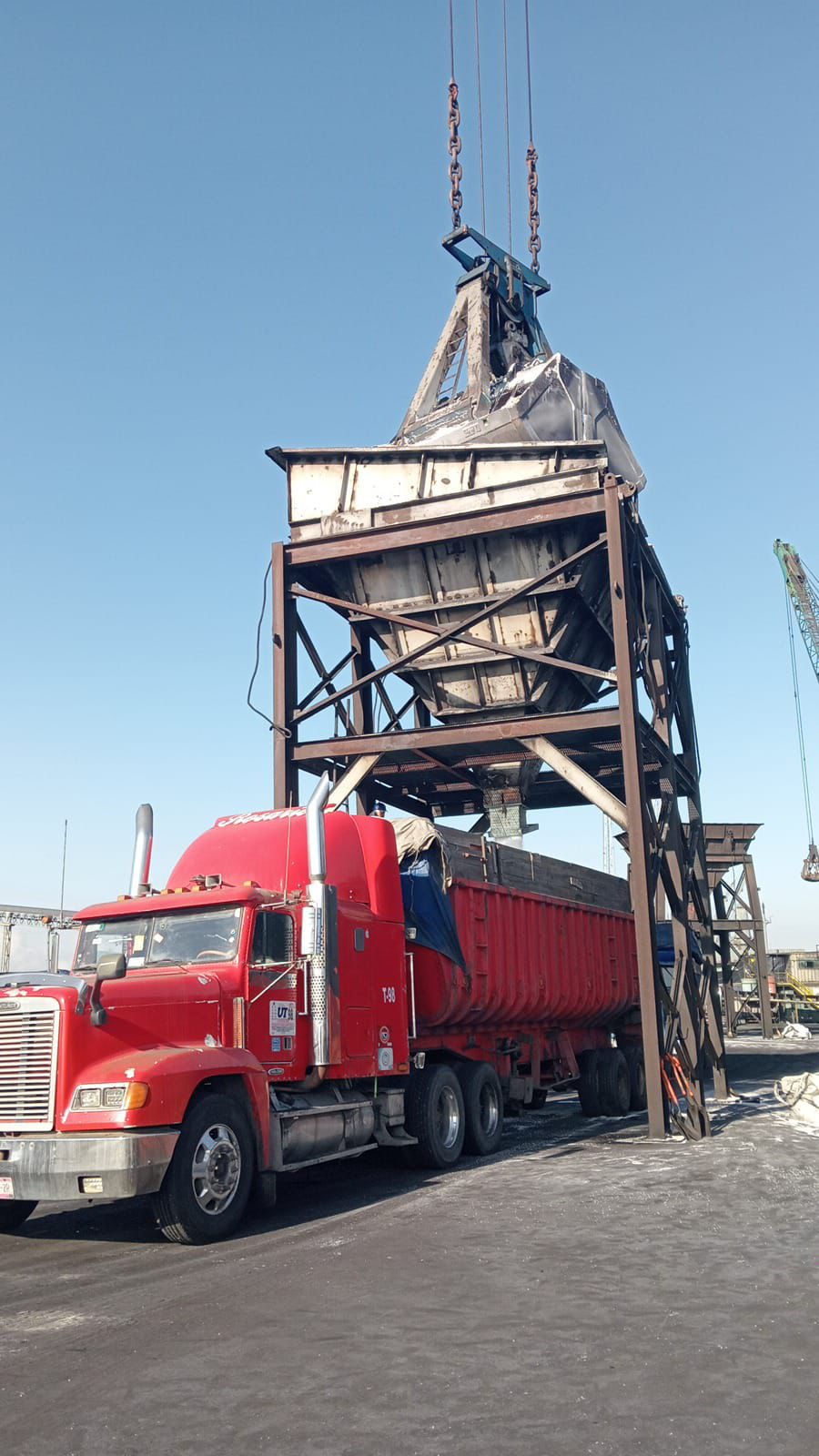 Camión rojo de carga estacionado bajo estructura metálica de descarga