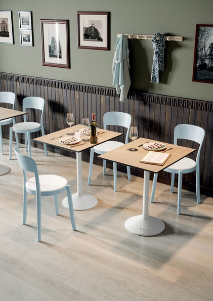 餐廳擺放兩張咖啡色方形白腳的桌子,搭配藍色餐椅