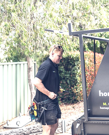 Home Plus Electrical electrician with tool belt beside the work trailer on a Canberra job