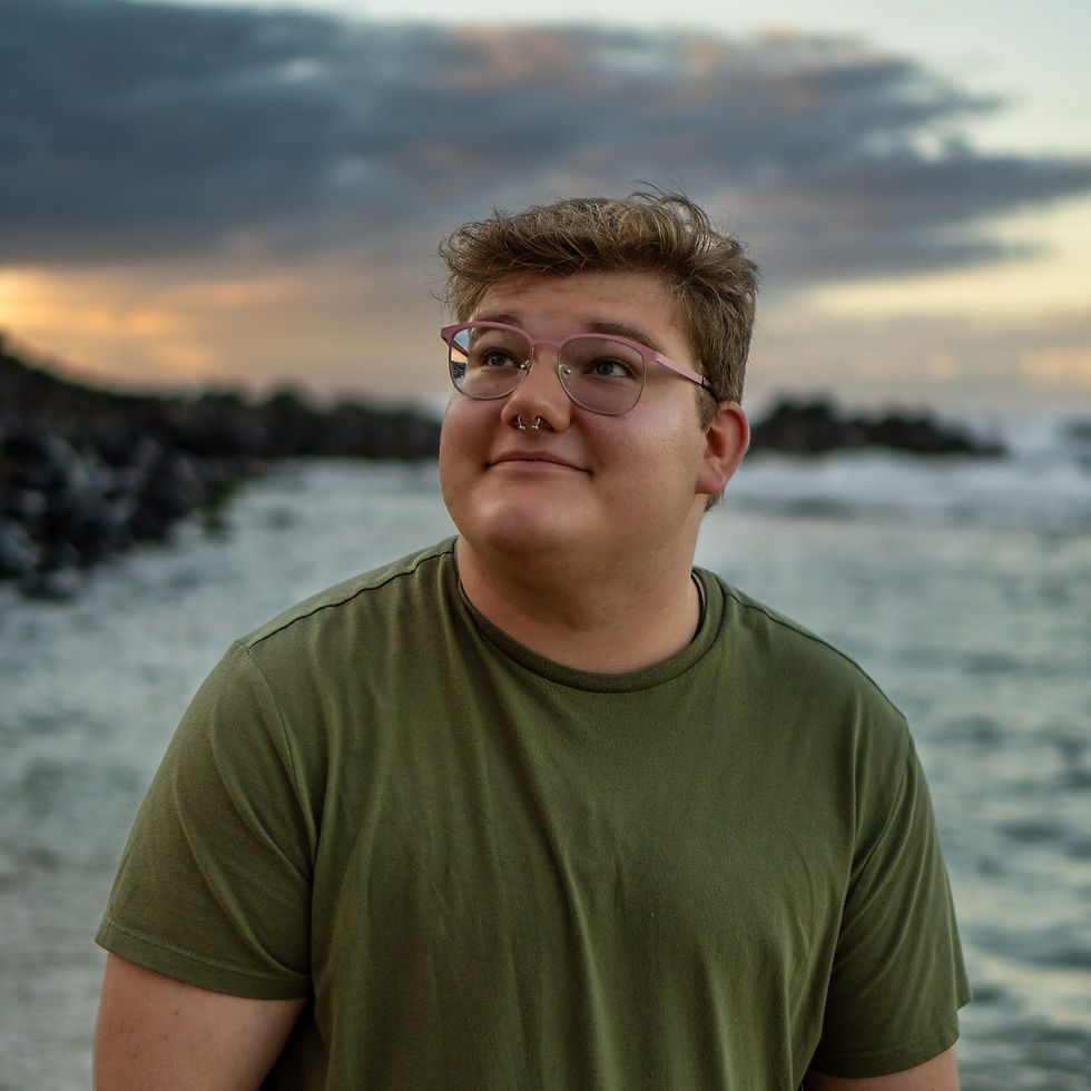 Young person with glasses looking up by the coast