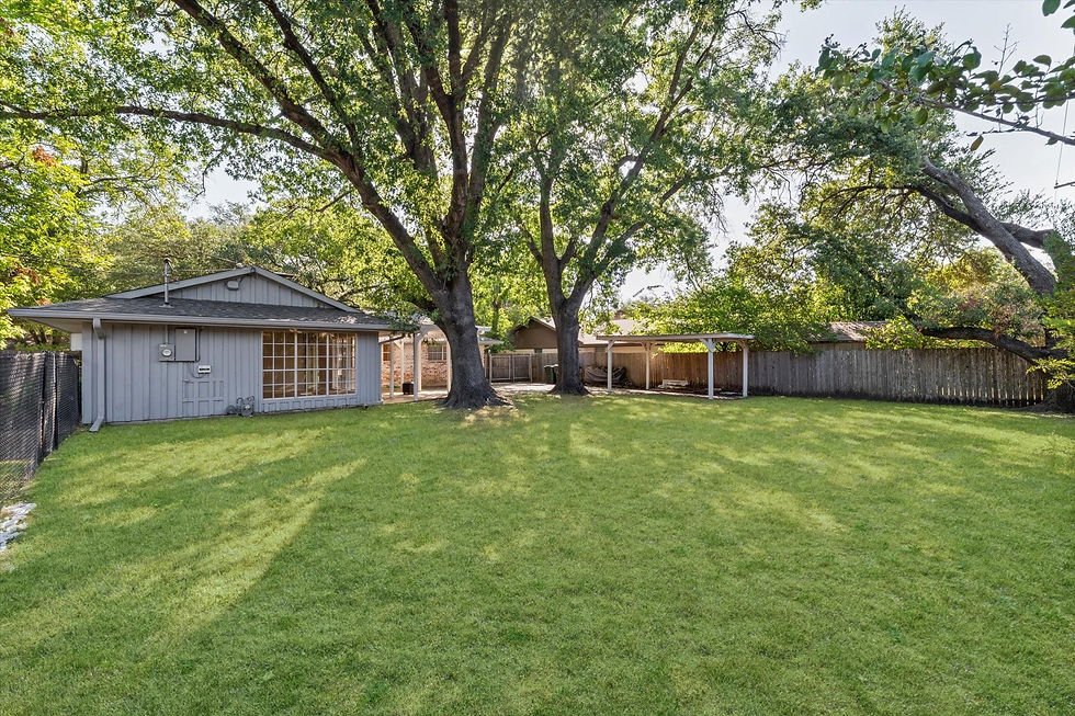 Wide-angle view of a leafy backyard with a covered portico and open lawn space.