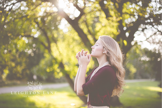 woman praying with a tree in the background