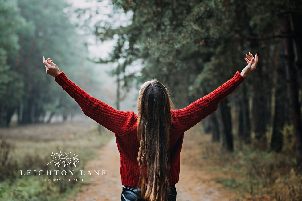 woman in red sweater with hands raised and trees in background