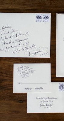 Daniel Cole calligraphy for custom wedding invitations and envelopes on a wooden surface.