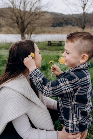 enfant glissant un pissenlit sur l'oreille de sa maman
