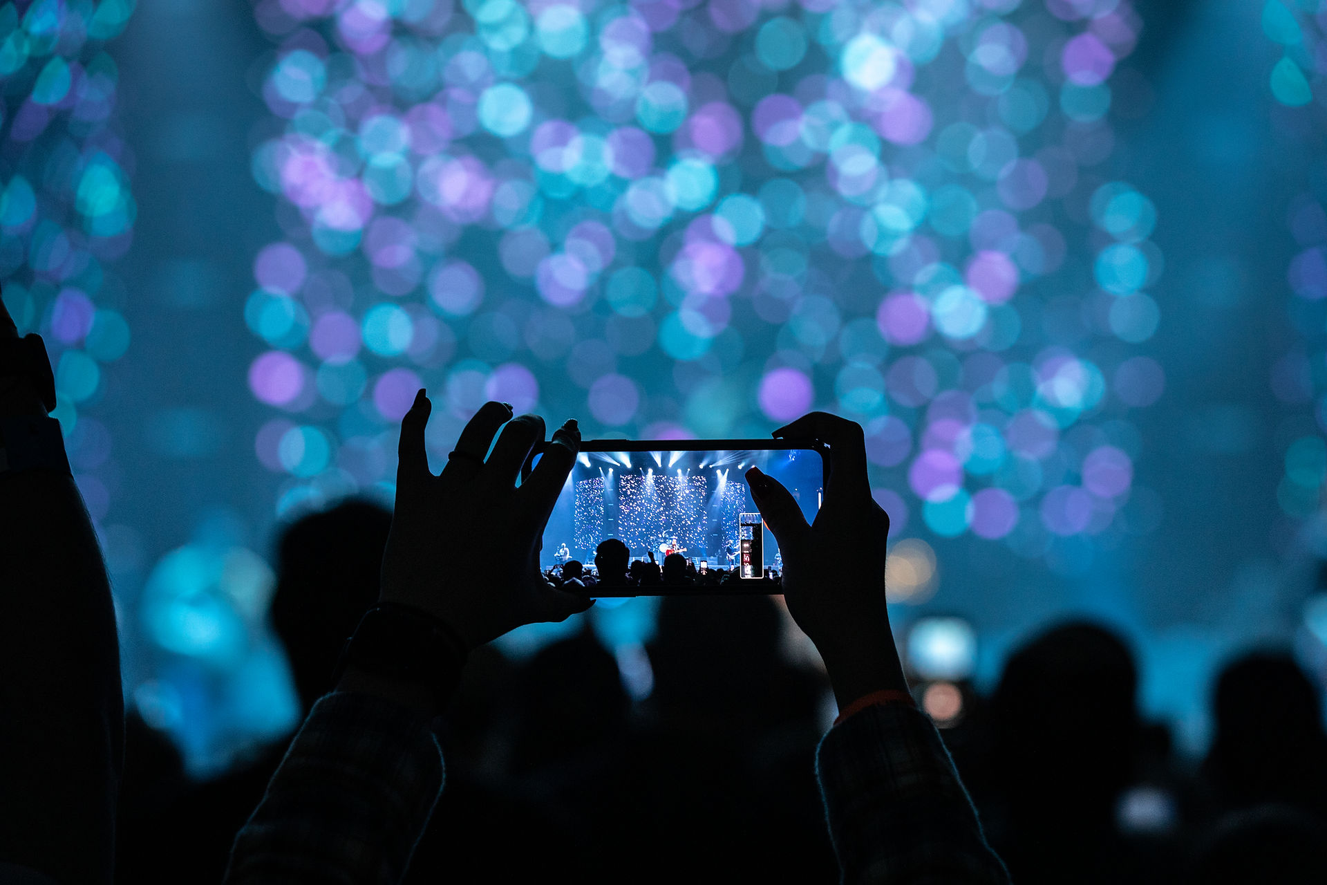A concert-goer taking a photo on their phone at a Luke Combs show