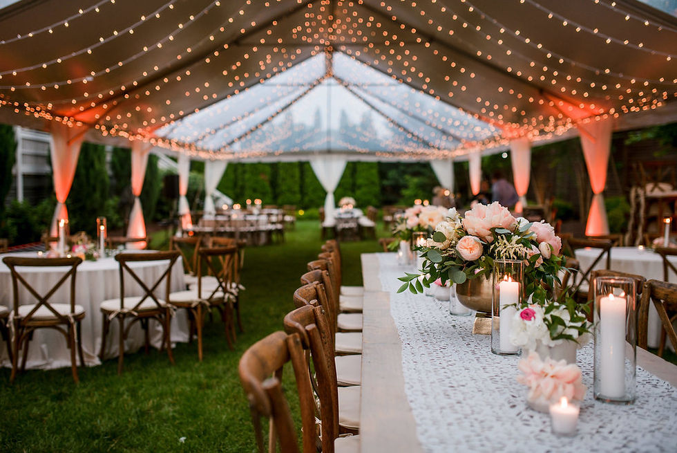 Elegant outdoor wedding setup under string lights with decorated tables, white tablecloths, floral centerpieces, and glowing candles.