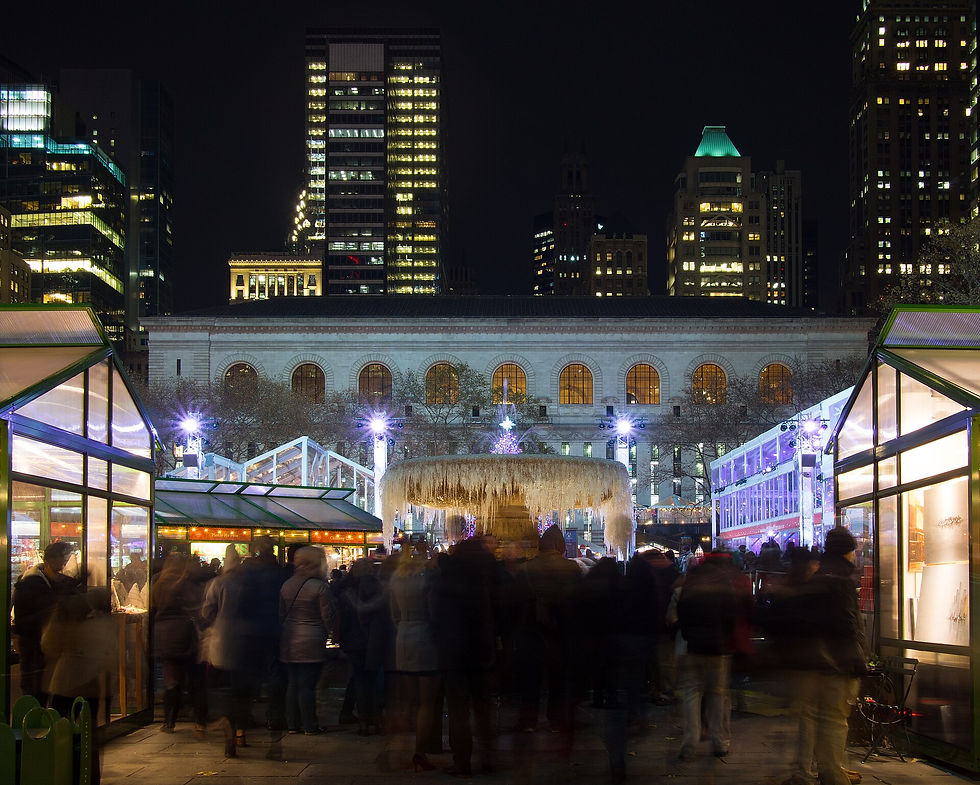 Visitors walking between illuminated holiday shops at Bryant Park Winter Village at night.