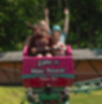 The Thriller rollercoaster at Land of Make Believe, with excited riders raising their hands and smiling as the coaster speeds along its track.