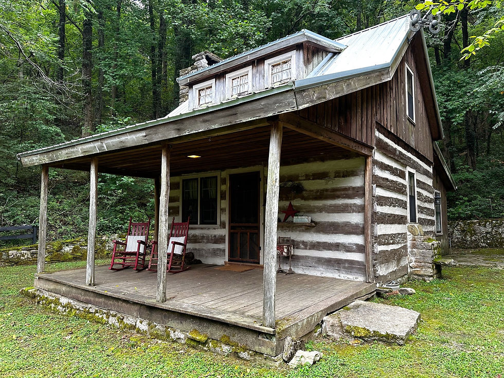 Rustic log cabin with a porch, two red rocking chairs, set in a lush green forest. Peaceful, natural setting with wooden texture.