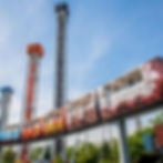 Monorail with Hershey's branding passes by colorful towers labeled Hershey's, Reese's, and Kisses, set against a clear blue sky.