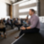 Speaker sitting on stage addressing a seated audience