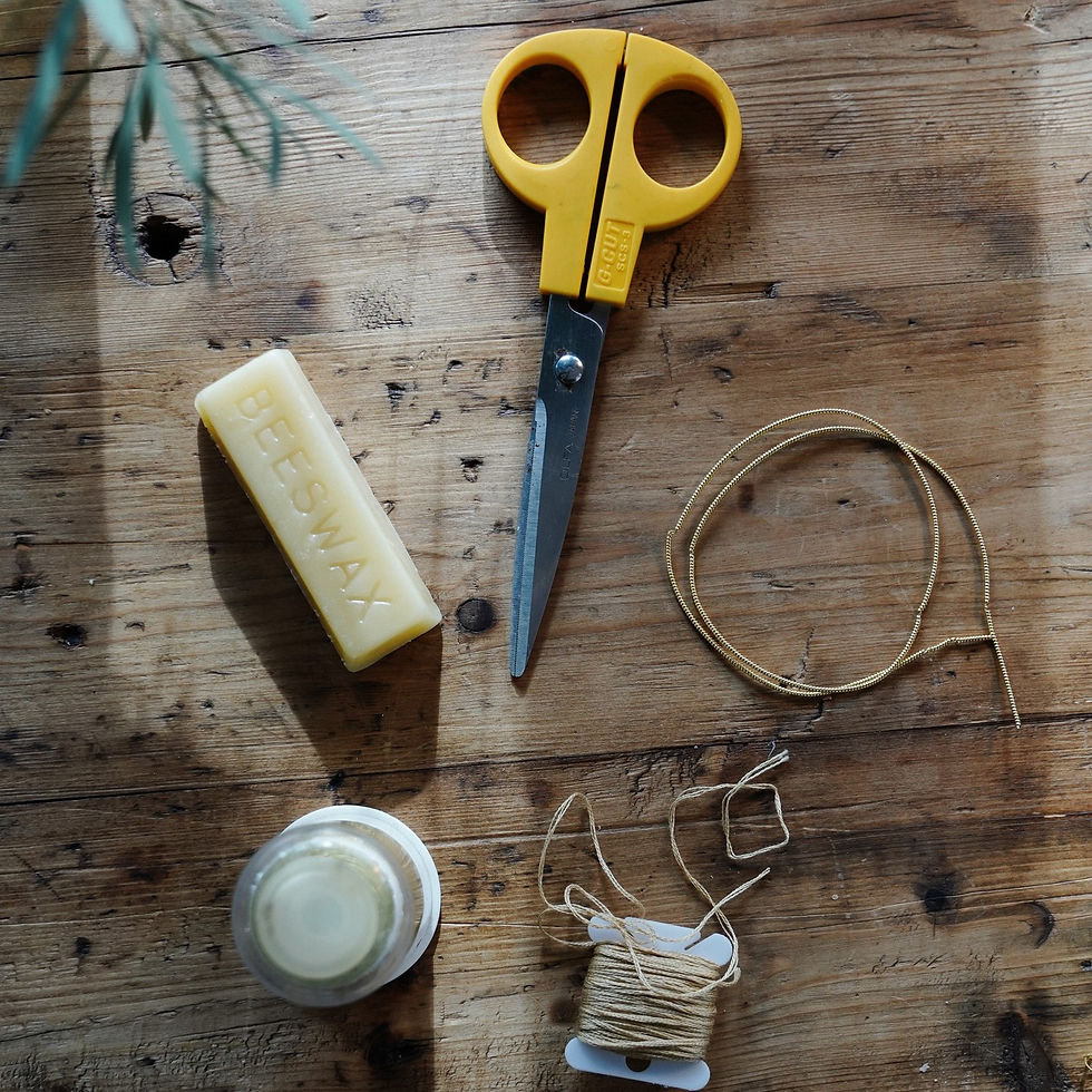 Flat play of embroidery materials on an oak table - scissors, beeswax, gold thread.