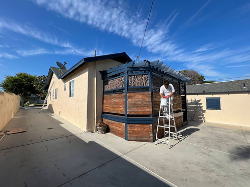 Home with private patio on the back. A man is white clothing is standing on a ladder with his hand in a bucket