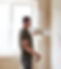 Man standing near a wall with a hand paint sprayer spraying paint on the wall