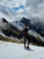 Man looking over a mountain ridge at mountain peaks