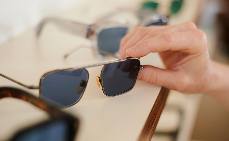 Eine Sonnebrille wird in der Hand gehalten