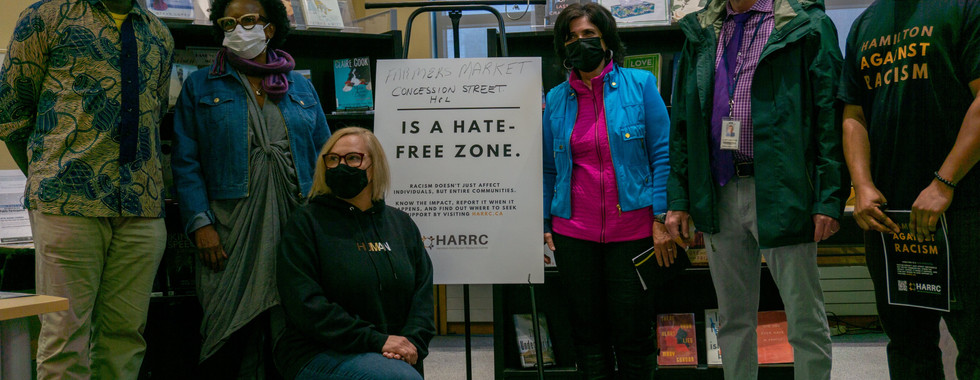 Representatives from HARRC and other community groups gather for a photo by a Hate Free Zone poster.