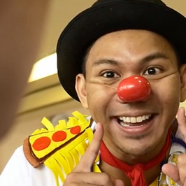 a man wearing a clown costume and indicating a sign for smiling