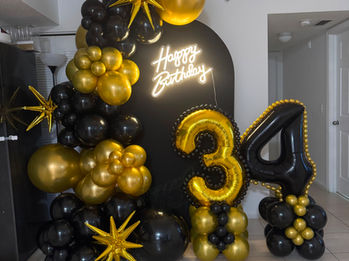 Black and gold 34th birthday balloon backdrop with large number balloons.
