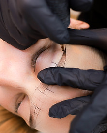 the permanent makeup artist stretches the skin in the area of the eyebrows to perform the