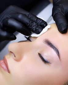 close-up of the master wipes the remnants of paint for coloring eyebrows with a cotton spo