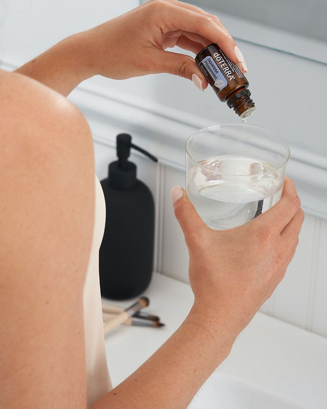 Frau tropt Ätherisches Öl Peppermint von doterra in ein Glas
