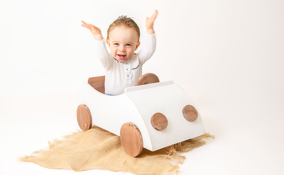 Jongetje in een houten autootje tijdens een kinderfotoshoot