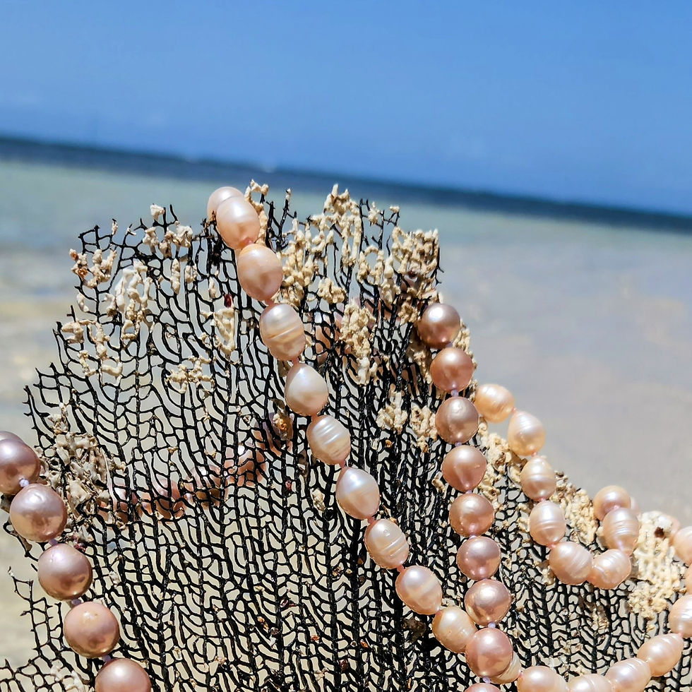 Thumbnail: Pearl necklace on coral against beach background, sea in a sunny day.