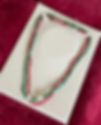 Green and red beaded necklace on white stand The Emerald Eye's Treasure by Pirate Jewelry Co.