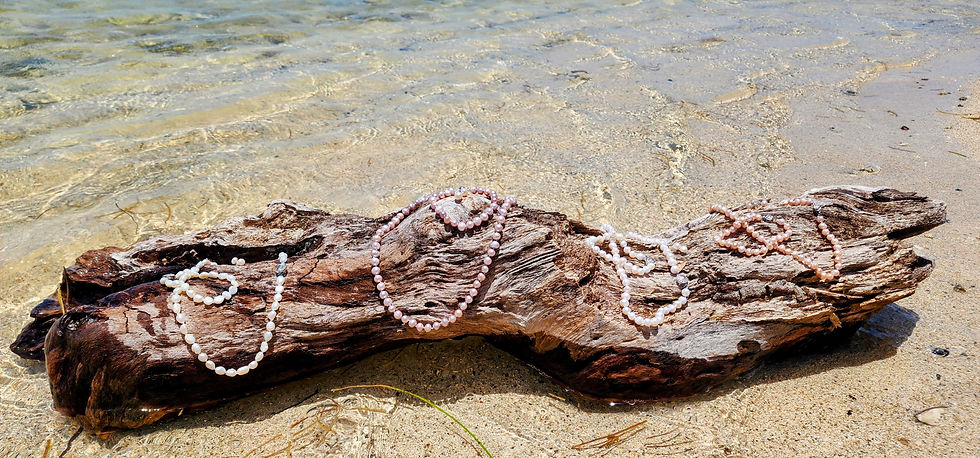 Thumbnail: White pearl necklaces displayed The Admiral's White South Sea Pearl Set on driftwood near water.