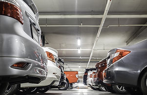 Vista em ângulo baixo de um estacionamento coberto com diversas vagas ocupadas por veículos de diferentes mode