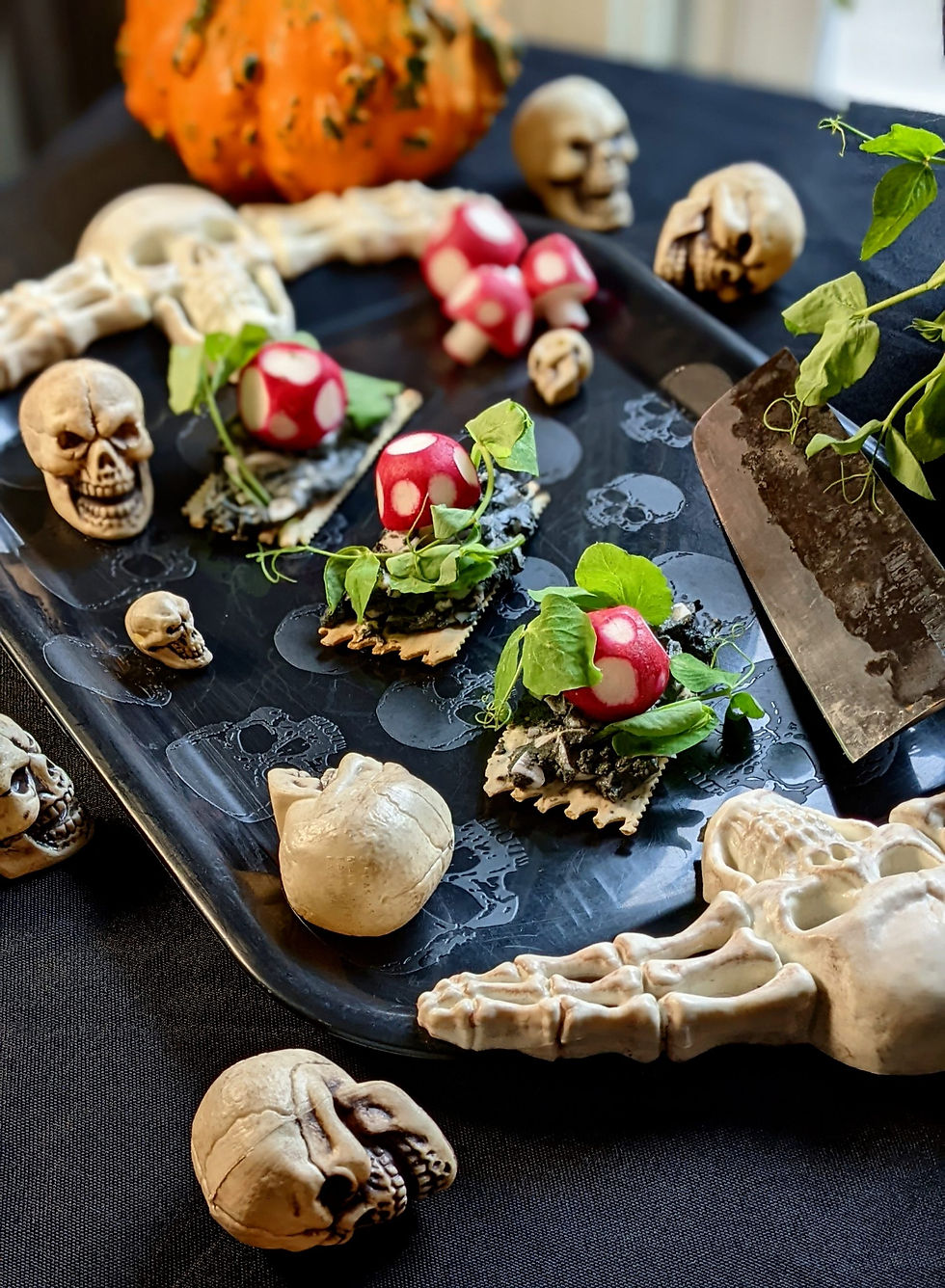 Spooky Halloween tray with skulls, bones, red mushrooms, and green leaves beside an orange pumpkin