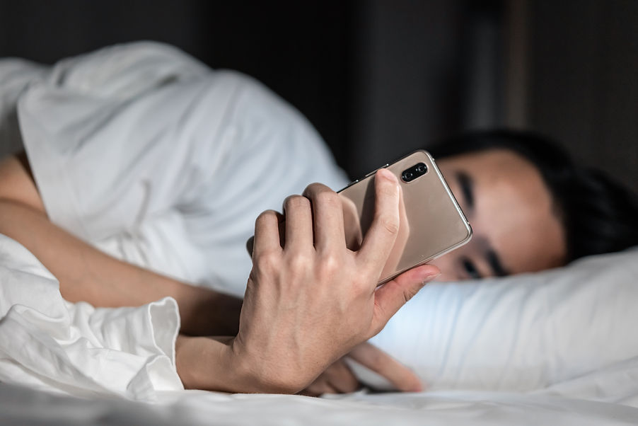 man-holding-phone-while-laying-in-the-bed