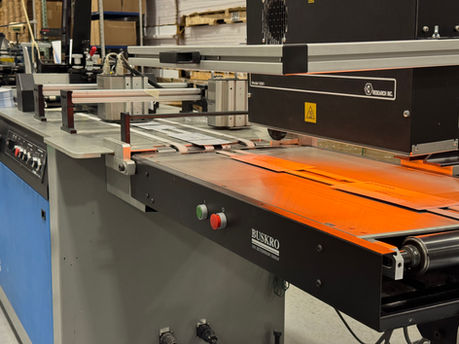 A Buskro inkjet system applies variable data to individual direct mail pieces, while a UV curing station beneath the printhead helps cure the ink immediately after printing.