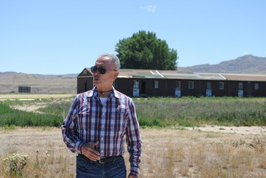 George Takei stands in front of the barrack at Heart Mountain.