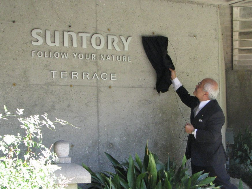 JACCC staff member Chester Ikei unveils the Suntory Terrace sign.
