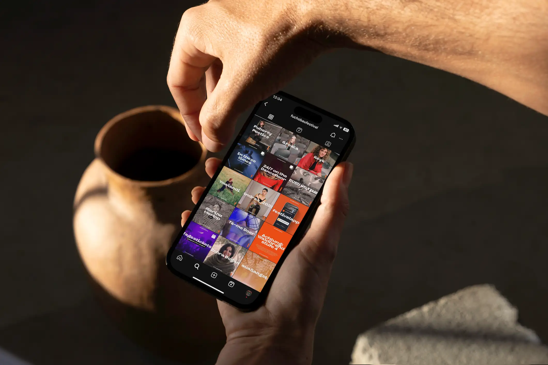 iPhone in einer Hand mit einer Übersicht des Social Media Accounts vom Fuchsbau Festival