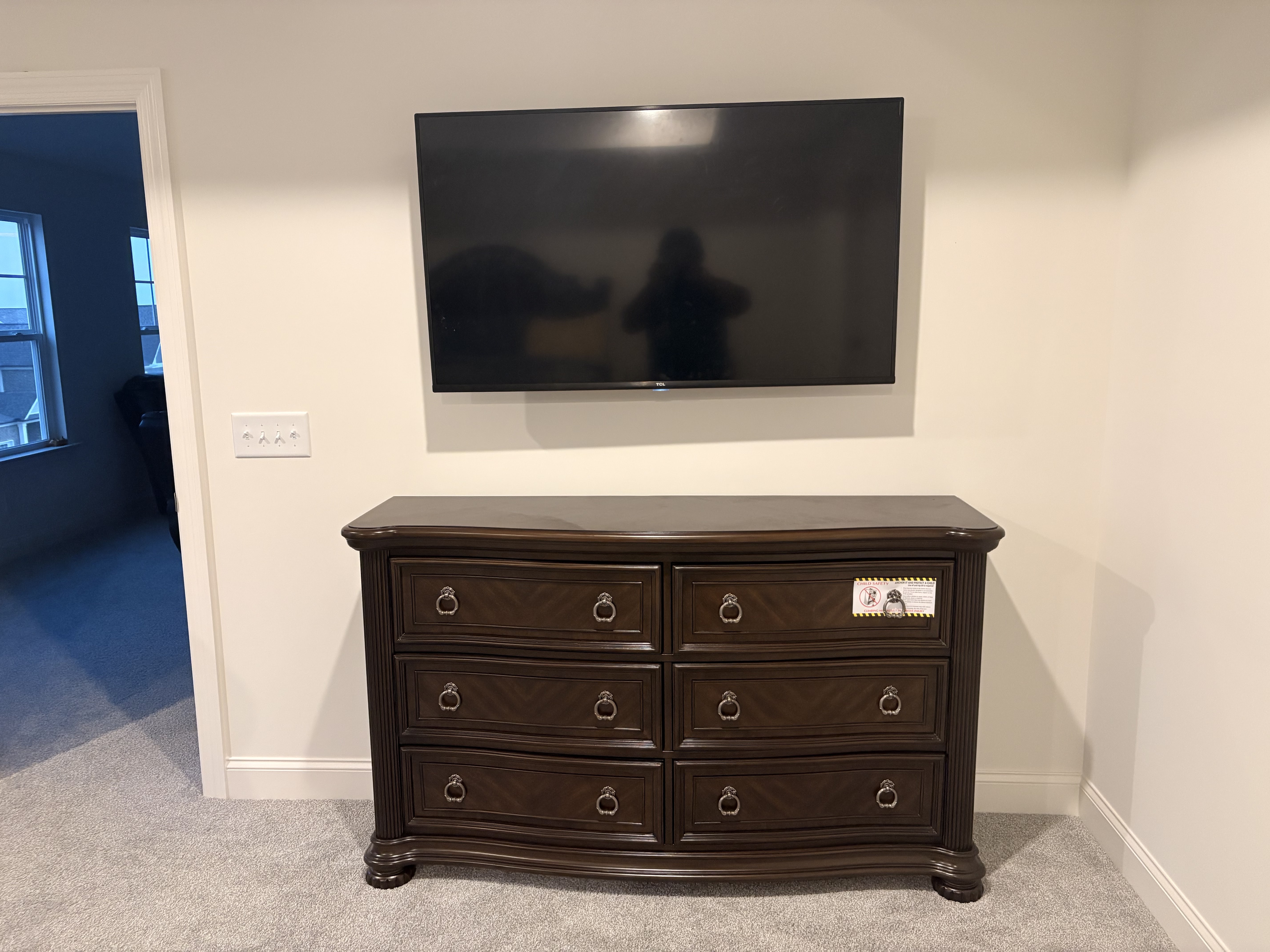 MOUNTIN TVs wall-mounted television above a dark wooden dresser