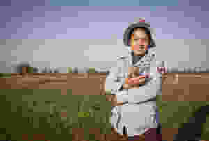 Cambodian lady in protective clothing holds a Tanzanian Giant-pouched rat in a Cambodian minefield