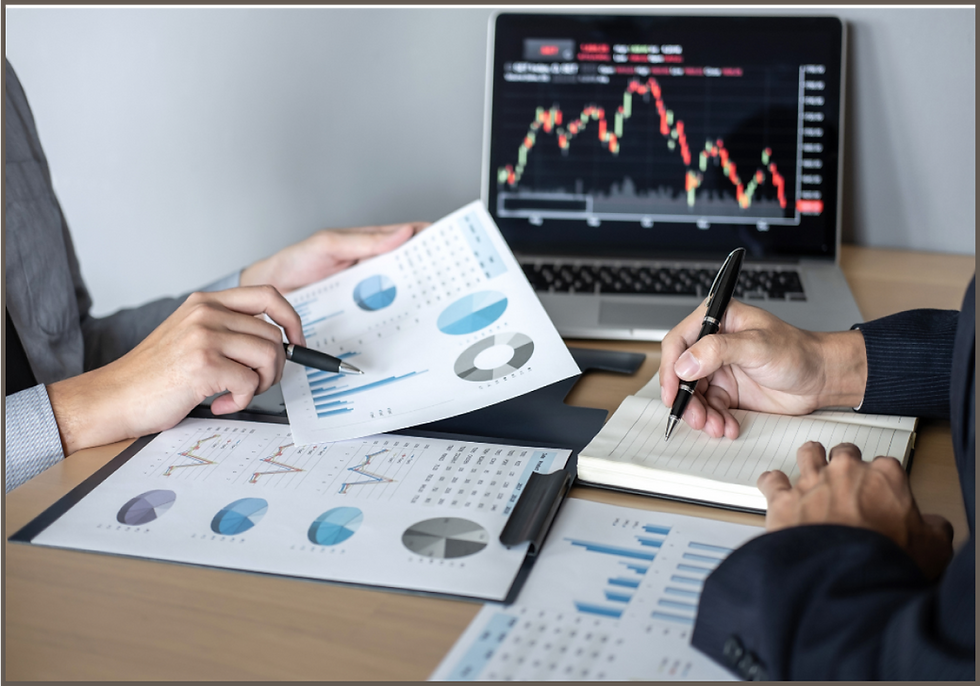 Two people analyzing charts and graphs with a laptop displaying a stock market trend. Papers and pens are on a wooden desk.
