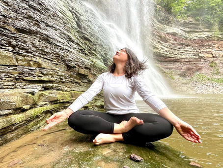 Sitting in easy pose near waterfall at Ball’s Falls, gazing up at the sky, surrounded by nature and peaceful energy.