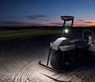 WayRake autonomous bunker rake maintaining a golf course bunker at night